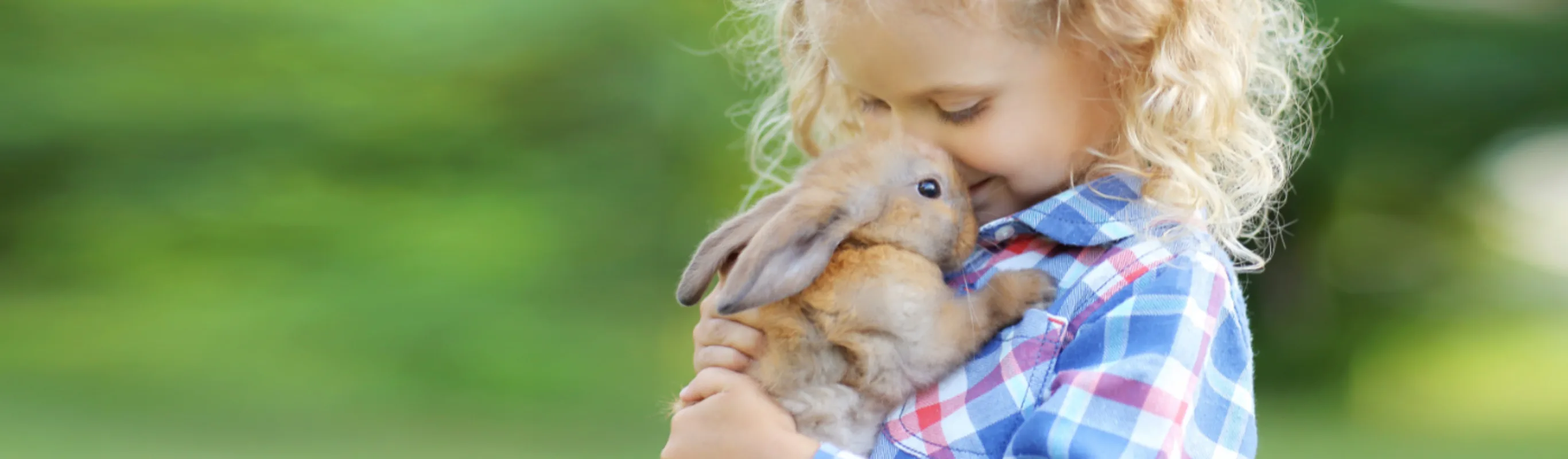 Girl Hugging a Brown Rabbit Outside